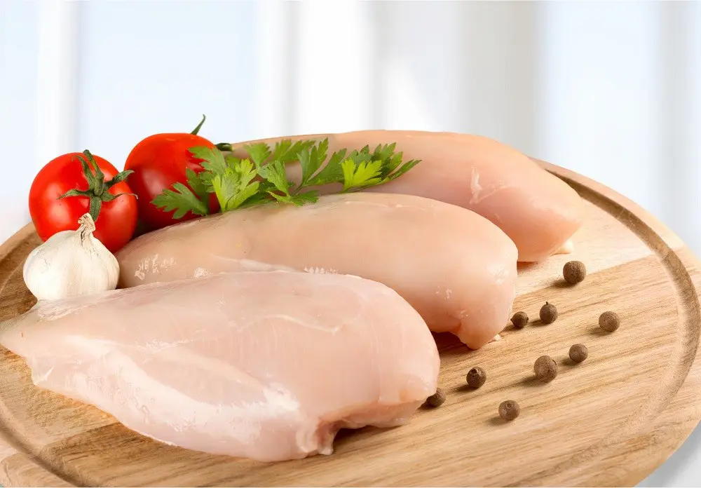 Raw chicken breasts on a wood cutting board