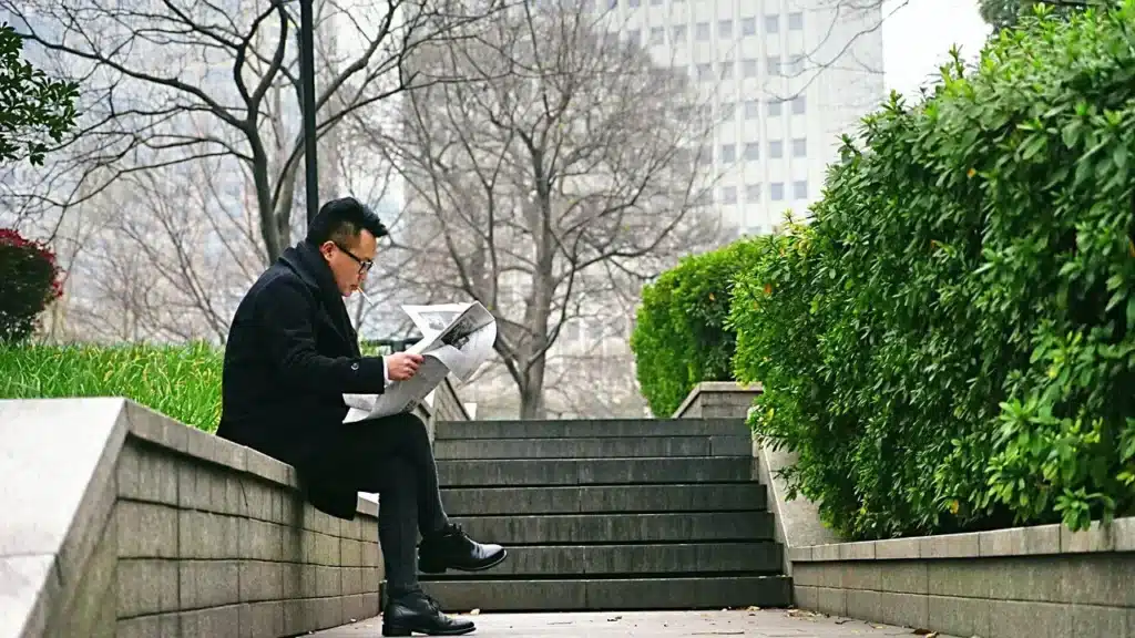 Gentleman sitting on a stoop reading a paper